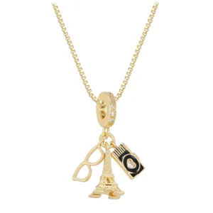Close-up of gold-plated necklace with Eiffel Tower, camera, and glasses charms.