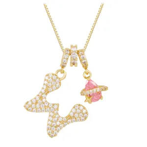 Detailed close-up of gold necklace with butterfly and pink planet zircon pendants