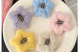 Vue détaillée de cinq barrettes étoiles en peluche colorées sur une assiette blanche décorative