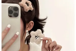 Gros plan d'une jolie pince à cheveux étoile en peluche beige portée par un modèle.