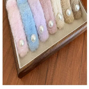 Détail macro de pinces à cheveux en peluche colorées avec de grandes perles blanches.