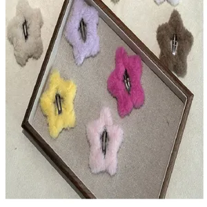 Vue détaillée de pinces à cheveux en forme d'étoile en peluche sur un plateau en lin.
