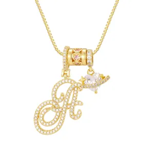 Detailopname van een vergulde ketting met letter A en hart- en Saturnus-bedeltjes.