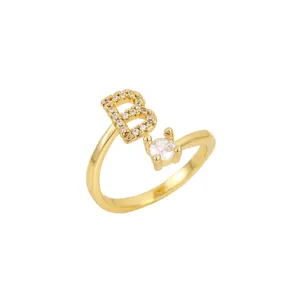 Vue détaillée d'une bague ouverte dorée avec lettre B scintillante et pierre ronde