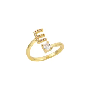 Vue détaillée d'une bague ouverte dorée ornée d'une lettre E scintillante en zircone