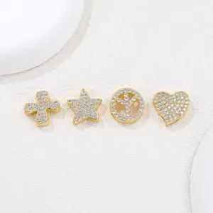 Macro detail of four gold zircon-encrusted charms in star, heart and peace sign shapes