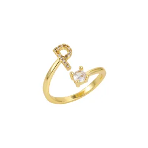 Gros plan d'une bague dorée ajustable avec lettre R et pierre précieuse claire