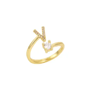 Vue détaillée d'une bague ouverte dorée avec une lettre V scintillante et une pierre ronde