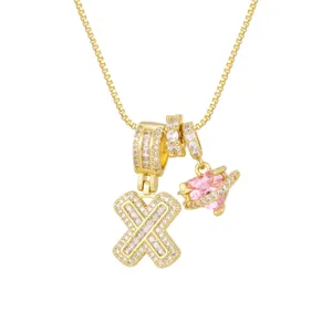 Gros plan sur l'initiale 'X' plaquée or 18 carats et charms planète cœur rose avec zircons.