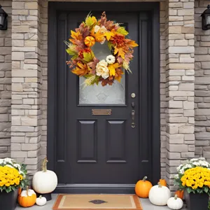 Autumn wreath with pumpkins and eucalyptus leaves hanging on a black front door