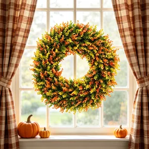 Artificial eucalyptus wreath hanging in a window with pumpkins and plaid curtains.