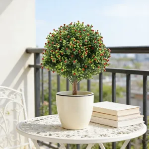 Detail van een kunstmatige Aglaia odorata plant met rode bessen in een pot.
