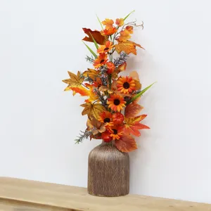 Detailed view of autumn floral arrangement with maple leaves and pumpkins in a rustic vase
