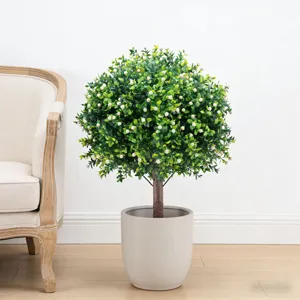 Realistische kunstmatige vormsnoeplant in een witte pot in een moderne woonkameromgeving.