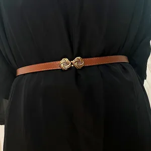 Slim leather belt for women, vintage dress waist accessory with metal buckle for stylish look.