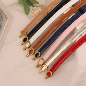 Close-up detail of multi-color skinny patent leather belts with elegant round metal buckles.