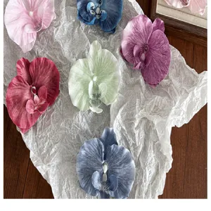 Detail view of multicolored silk orchid flower hair claw clips on textured paper