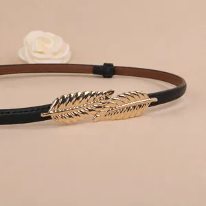 Close-up detail of the stylish black thin leather belt with a golden leaf metal buckle.