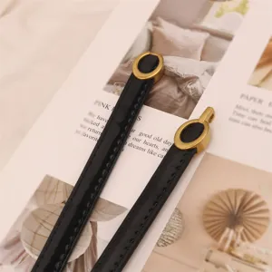 Thin black patent leather belt detail view, elegant metal buckle accessory for women dresses.
