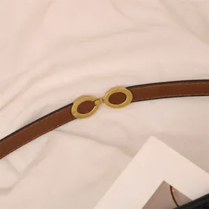 Detailed close-up view of women's brown leather belt featuring a stylish gold-tone oval buckle.