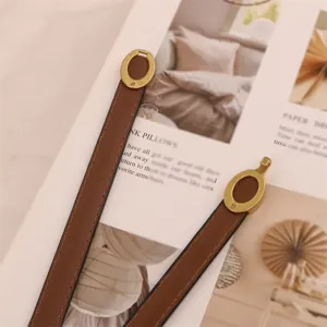 Detailed shot of a thin brown women's leather belt with retro gold oval buckle, minimalist style.