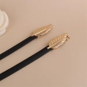 Detailed view of women skinny black leather belt featuring elegant gold leaf metal buckles.
