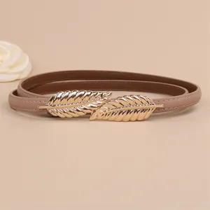 Detail view of women genuine leather thin belt with gold leaf buckle, elegant waist accessory.