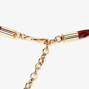 Close-up detail of golden metal hook clasp and red braided leather waist chain strap.