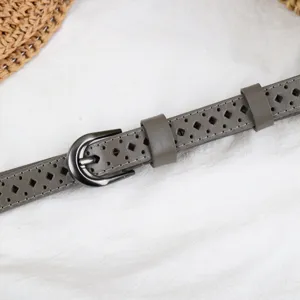 Detailed view of women grey leather belt featuring hollow out geometric patterns and metal buckle.