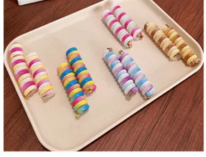 Macro view of colorful telephone wire hair ties arranged in a beige display tray.