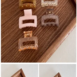 Detail view of 4cm colorful square plastic hair claw clips arranged on a wooden tray