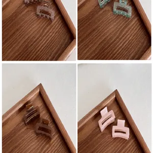 Detailed macro view of 4cm square mini hair claws in various colors on a wooden tray