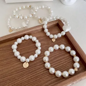 Elegantes Perlen-Haargummi-Armband im koreanischen Stil mit Herzanhängern auf Holztablett.