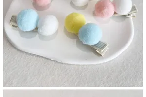 Gros plan sur de mignonnes pinces à cheveux pompons pastel sur assiette.
