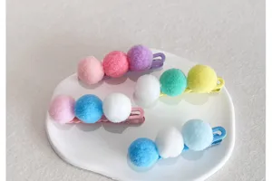 Vue en gros plan de mignonnes barrettes à cheveux en pompons en peluche sur assiette