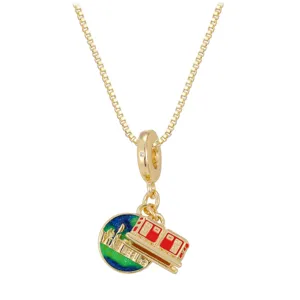 Detailed macro view of gold-toned pendant necklace with red tram and city globe charms