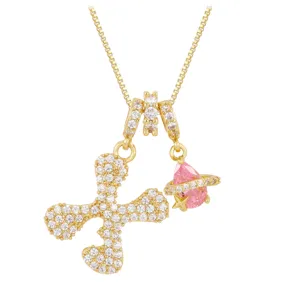 Macro view of gold-plated box chain with letter X and pink planet stone pendants