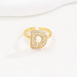Gedetailleerd overzicht van een gouden open ring met letter D bezet met zirkonia steentjes