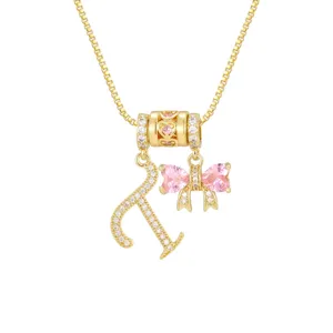 Detail einer Goldkette mit Buchstabe A und rosa Schleifenanhänger mit Zirkonia-Besatz