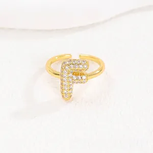 Gedetailleerde detailopname van een gouden ballonletter F ring met fonkelende steentjes
