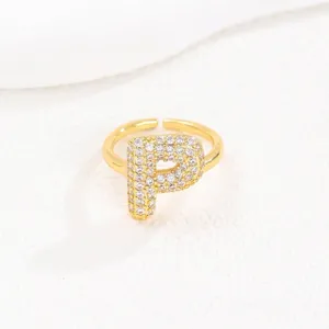 Gedetailleerde close-up van een vergulde open ring met de letter P en glanzende steentjes