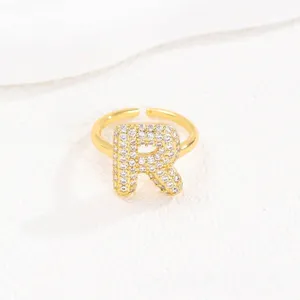 Gedetailleerde weergave van een goudkleurige bubble letter R-ring met pavé.