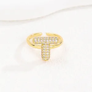 Detailopname van een vergulde open ring met een sprankelende kristallen letter T