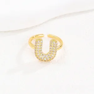 Detailweergave van een goudkleurige bubble letter U ring met pave-gezette zirkoon
