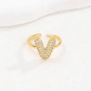 Detailweergave van een gouden verstelbare ring met een letter V bezet met zirkonia's