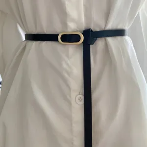 Minimalist thin leather belt detail view with gold oval buckle, versatile dress waist accessory.