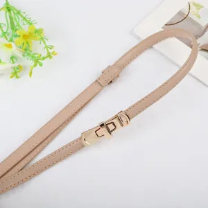 Detailed close-up of a stylish women thin leather dress belt with a polished gold metal lock buckle.