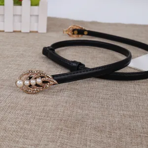 Detail view of black leather slim belt with gold leaf pearl buckle accessory for women style.