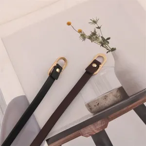 Close-up view of thin women's waist belts with elegant gold oval metal buckles and fine straps.