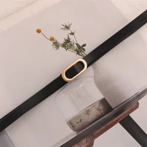 Minimalist thin black waist belt with golden oval buckle, elegant dress accessory detail.